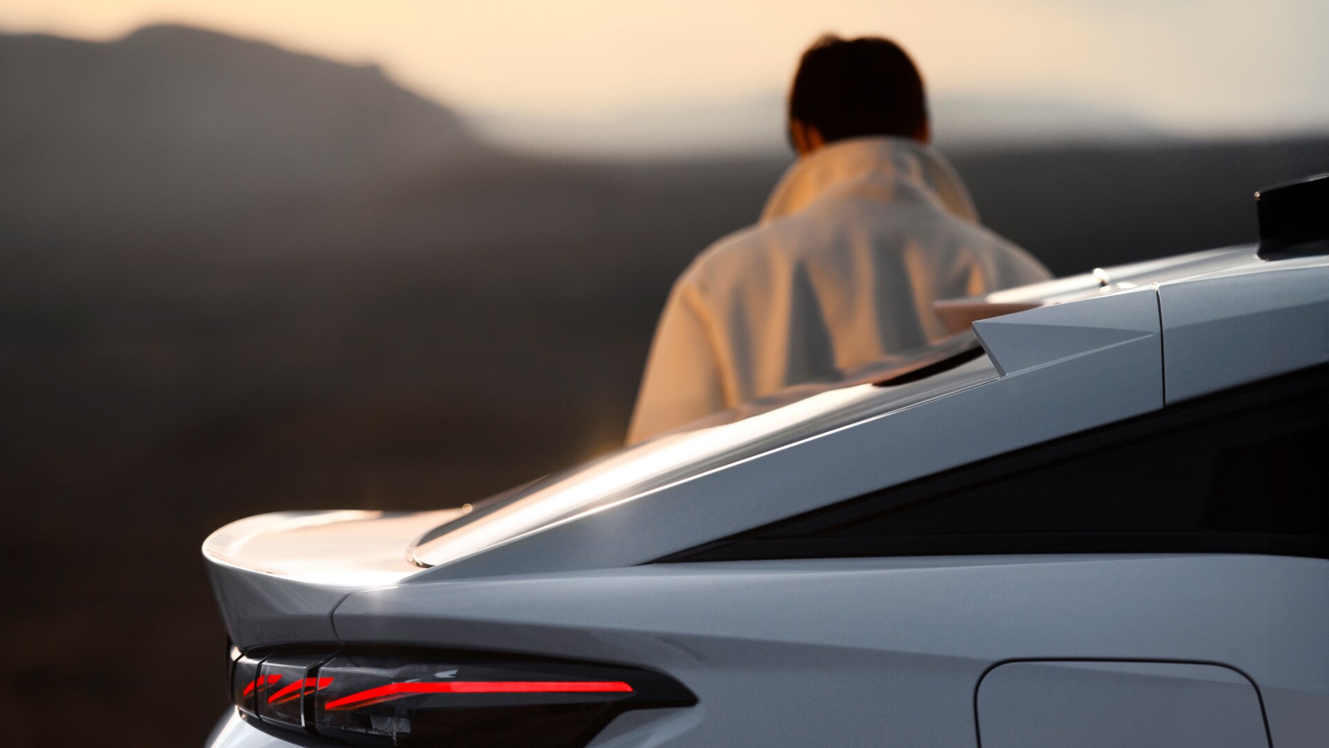 Vista posteriore PEUGEOT E-408, con una silhoutte che contempla il panorama